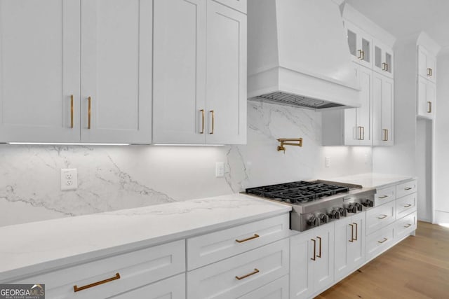 kitchen with white cabinetry, tasteful backsplash, stainless steel gas stovetop, and custom range hood