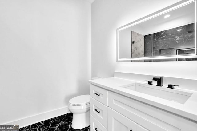 bathroom with tiled shower, vanity, and toilet