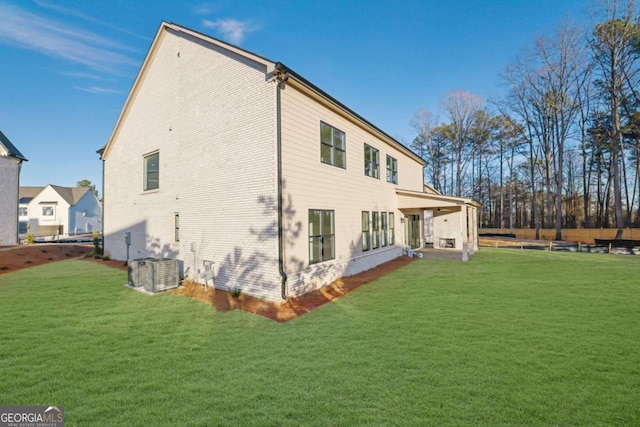 rear view of house with central AC and a lawn