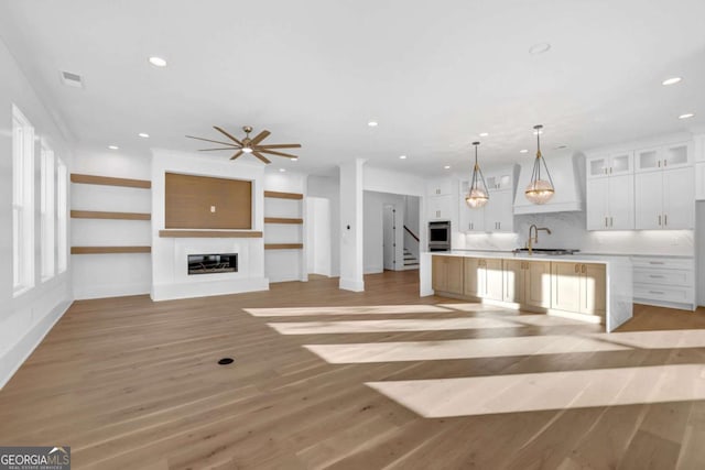 kitchen featuring decorative light fixtures, white cabinets, a center island, light hardwood / wood-style floors, and plenty of natural light