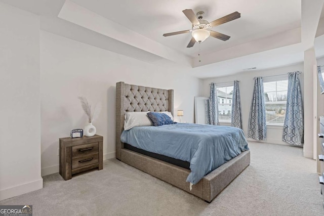 bedroom featuring ceiling fan, a raised ceiling, and light colored carpet