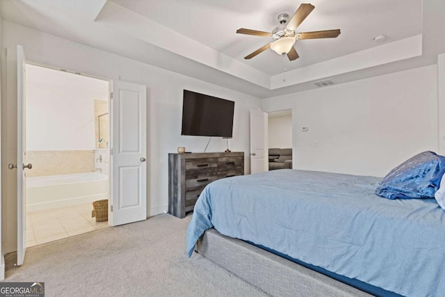 tiled bedroom with ceiling fan, a raised ceiling, and ensuite bath