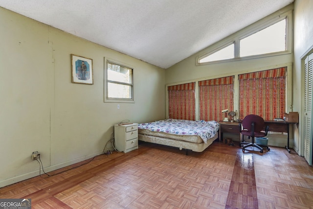 bedroom with parquet floors, vaulted ceiling, and a textured ceiling