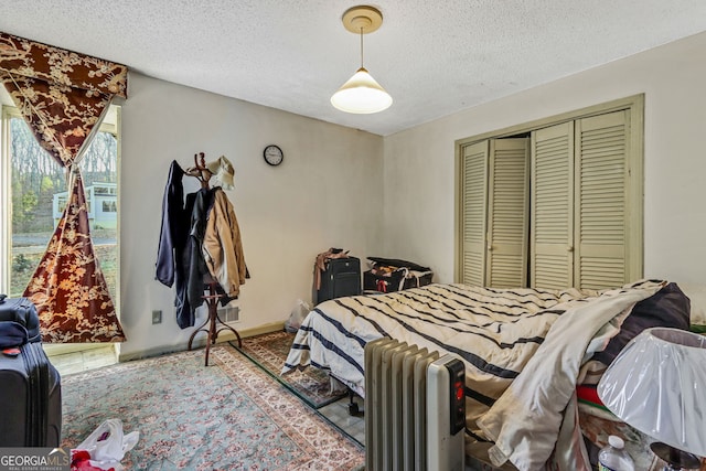 bedroom featuring radiator heating unit, a textured ceiling, and a closet