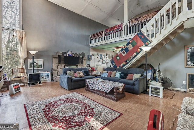 living room with a high ceiling, a wood stove, and parquet floors