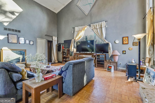 living room with a towering ceiling and light parquet flooring