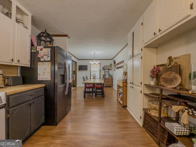 kitchen with crown molding, decorative light fixtures, a textured ceiling, light hardwood / wood-style flooring, and white cabinets