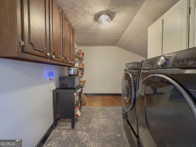 laundry room featuring dark hardwood / wood-style flooring, washing machine and dryer, cabinets, and a textured ceiling