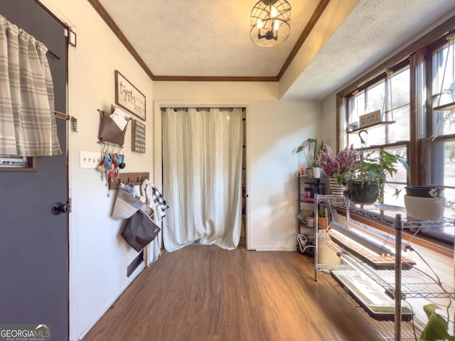 foyer entrance featuring hardwood / wood-style flooring, ornamental molding, and a textured ceiling