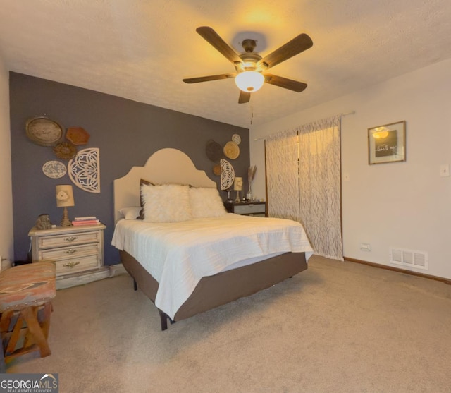 bedroom featuring a textured ceiling, light colored carpet, and ceiling fan