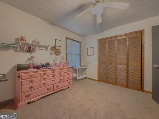 carpeted bedroom featuring ceiling fan, a closet, and a textured ceiling