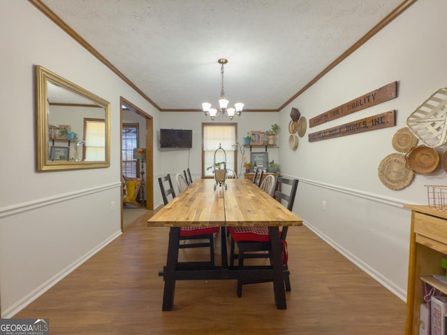 dining room with crown molding, dark hardwood / wood-style flooring, a textured ceiling, and a notable chandelier