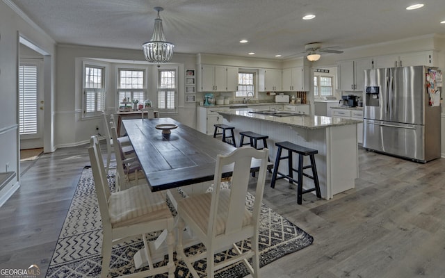 dining room featuring crown molding, sink, a textured ceiling, and light hardwood / wood-style flooring