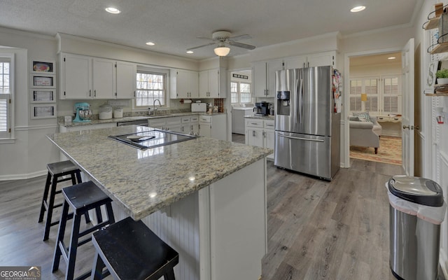 kitchen featuring appliances with stainless steel finishes, white cabinetry, sink, a kitchen bar, and a center island