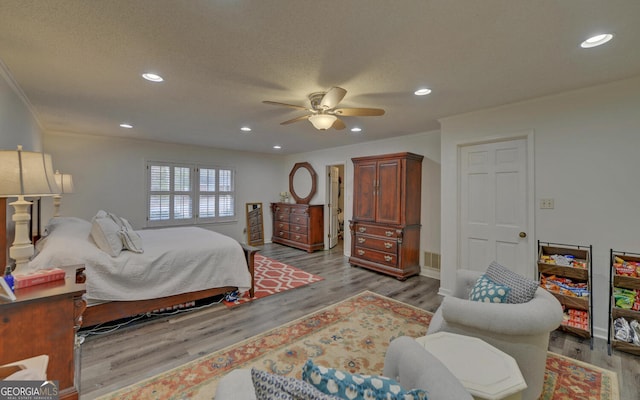 bedroom featuring ceiling fan, light hardwood / wood-style floors, and a textured ceiling