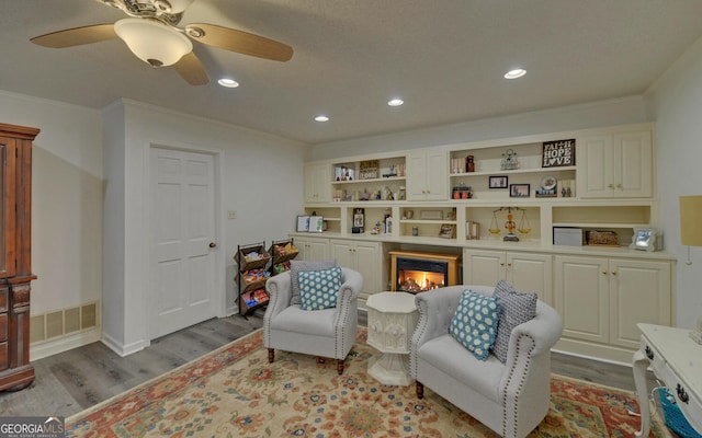 living area with crown molding, ceiling fan, and light hardwood / wood-style floors