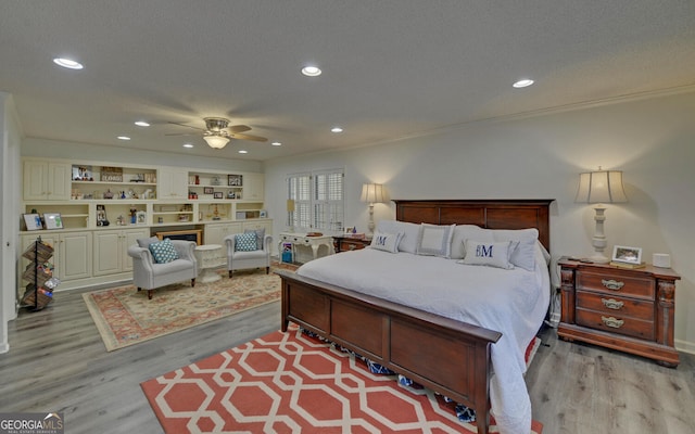 bedroom with a textured ceiling, ornamental molding, light hardwood / wood-style floors, and ceiling fan