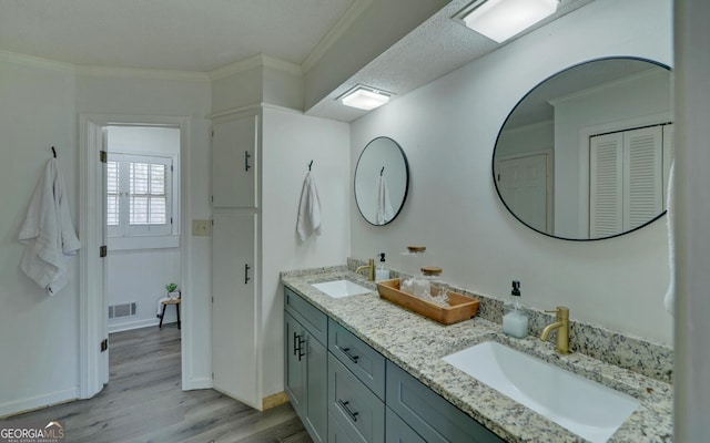 bathroom with crown molding, vanity, hardwood / wood-style floors, and a textured ceiling