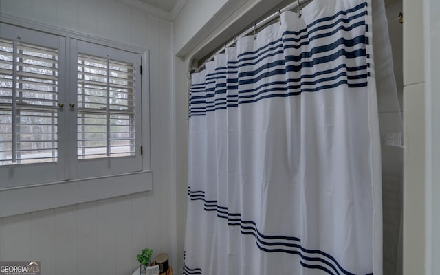 bathroom with ornamental molding and wooden walls