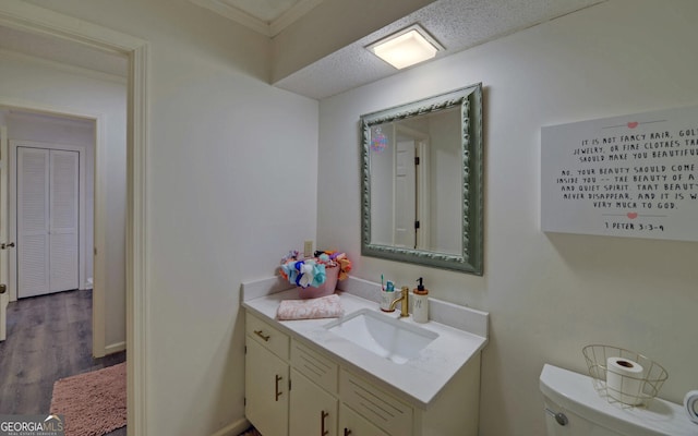 bathroom featuring vanity, hardwood / wood-style floors, a textured ceiling, and toilet