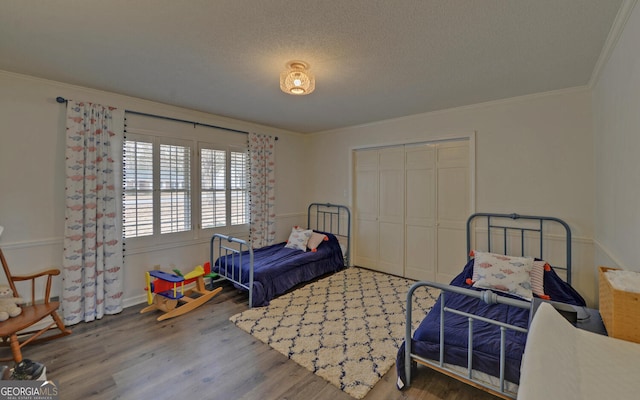 bedroom with wood-type flooring, a textured ceiling, crown molding, and a closet