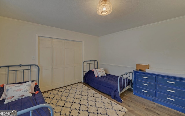 bedroom with light hardwood / wood-style floors, ornamental molding, a closet, and a textured ceiling