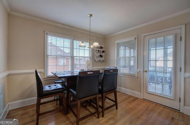 dining space featuring light hardwood / wood-style flooring, ornamental molding, and a chandelier