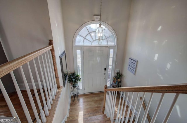 foyer featuring a notable chandelier, light hardwood / wood-style flooring, and a high ceiling