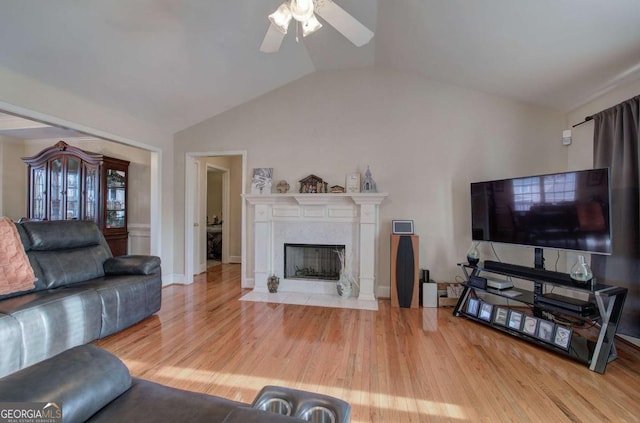 living room featuring vaulted ceiling, a premium fireplace, ceiling fan, and light wood-type flooring