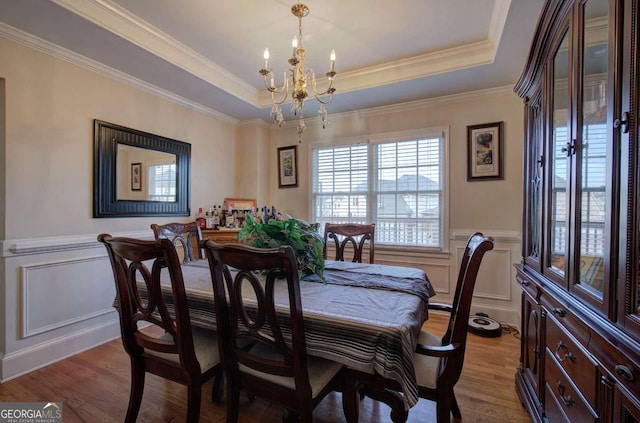 dining room with an inviting chandelier, a tray ceiling, light hardwood / wood-style flooring, and crown molding