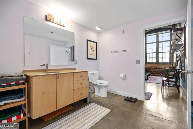 bathroom with toilet, brick wall, vanity, and concrete flooring