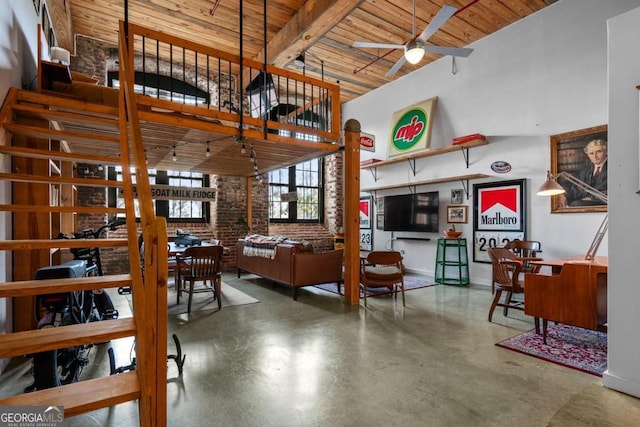 interior space with ceiling fan, beam ceiling, a high ceiling, brick wall, and wooden ceiling