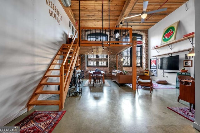 interior space featuring brick wall, high vaulted ceiling, beamed ceiling, ceiling fan, and wooden ceiling