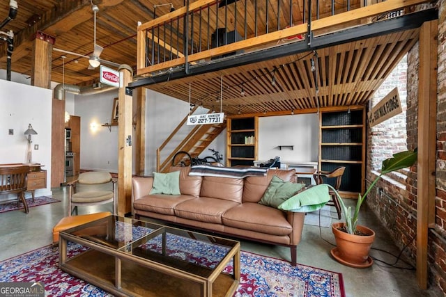 living room with concrete flooring, brick wall, and a towering ceiling