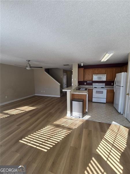 kitchen with sink, white appliances, dark wood-type flooring, a center island, and a textured ceiling