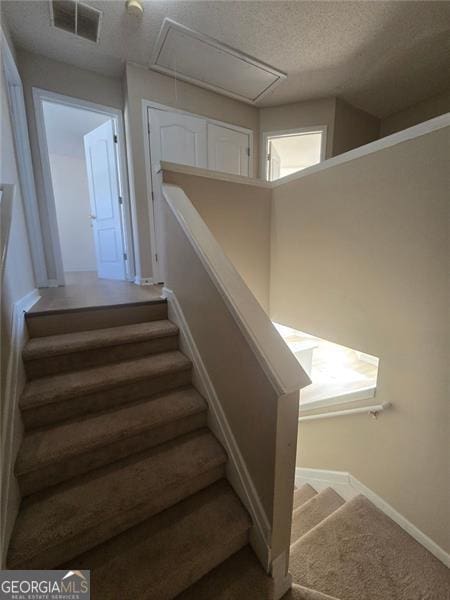 stairs with carpet flooring and a textured ceiling