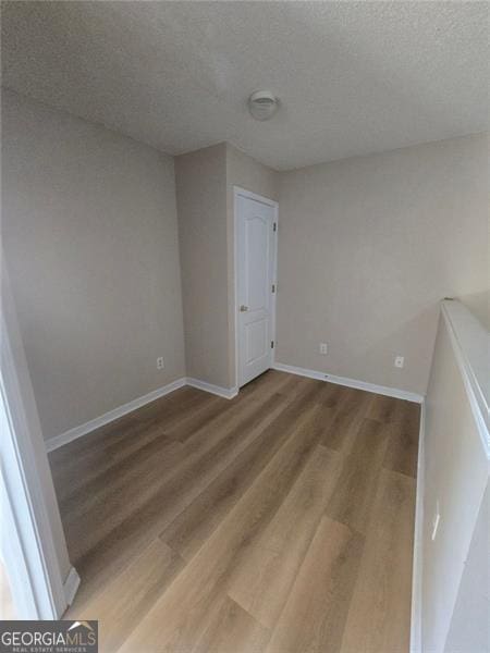 unfurnished room with wood-type flooring and a textured ceiling