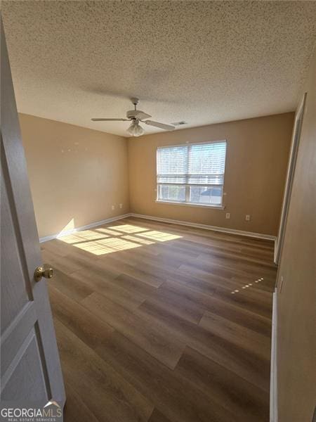 empty room featuring ceiling fan, dark hardwood / wood-style flooring, and a textured ceiling