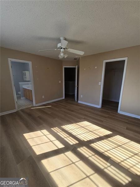 interior space featuring connected bathroom, a spacious closet, a textured ceiling, a closet, and ceiling fan