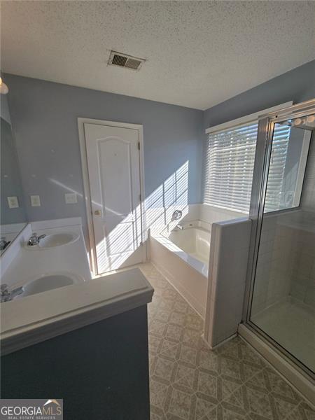 bathroom featuring vanity, separate shower and tub, and a textured ceiling