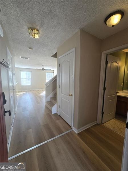 hallway with wood-type flooring and a textured ceiling