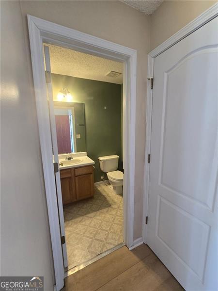 bathroom featuring vanity, a textured ceiling, and toilet