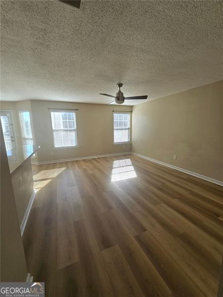 unfurnished room with a healthy amount of sunlight, wood-type flooring, and a textured ceiling