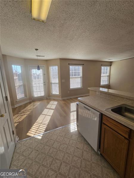 kitchen with pendant lighting, white dishwasher, sink, and a textured ceiling