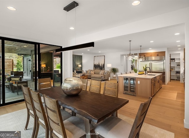 dining space featuring sink, wine cooler, and light hardwood / wood-style flooring