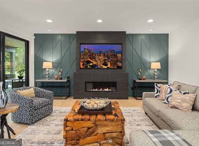 living room featuring a tiled fireplace and hardwood / wood-style floors