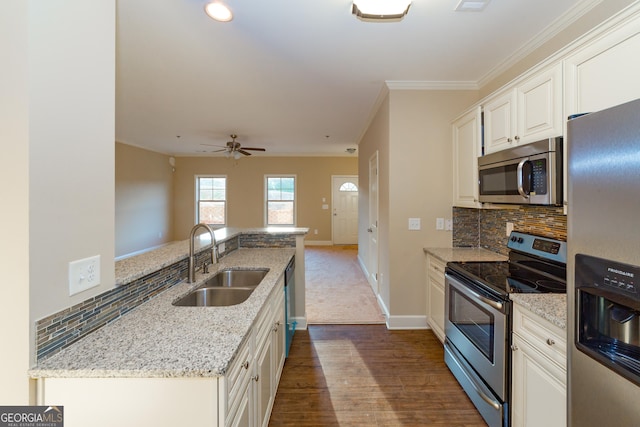 kitchen with a sink, white cabinets, ornamental molding, appliances with stainless steel finishes, and tasteful backsplash