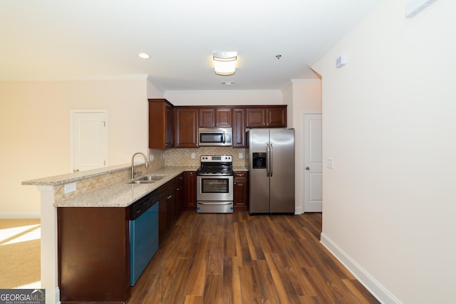 kitchen with appliances with stainless steel finishes, a peninsula, a sink, crown molding, and backsplash