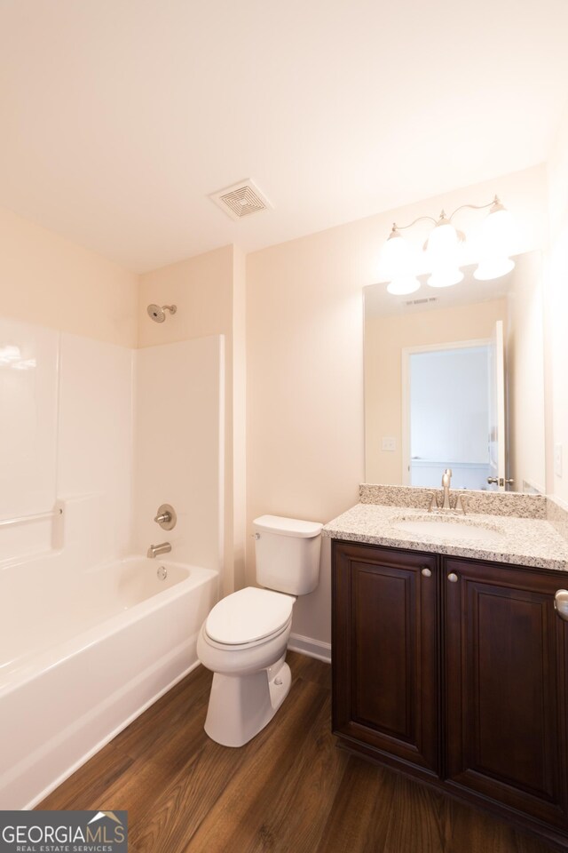 full bathroom with hardwood / wood-style flooring, shower / washtub combination, vanity, and toilet