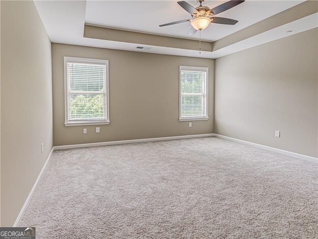 unfurnished room featuring a ceiling fan, visible vents, baseboards, carpet, and a raised ceiling